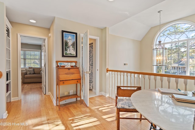 interior space with light hardwood / wood-style flooring, vaulted ceiling, and a notable chandelier