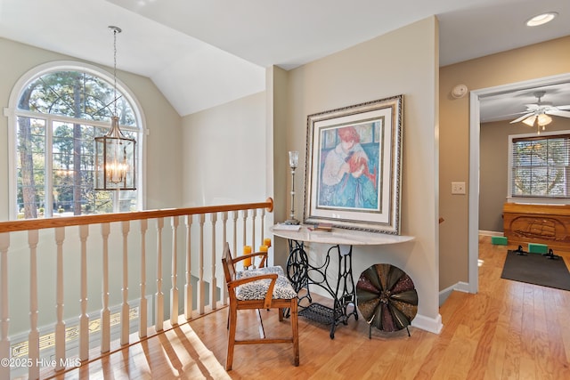 corridor featuring light hardwood / wood-style flooring, an inviting chandelier, and lofted ceiling