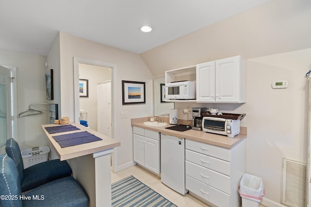 kitchen with white cabinets, white appliances, light tile patterned floors, and vaulted ceiling