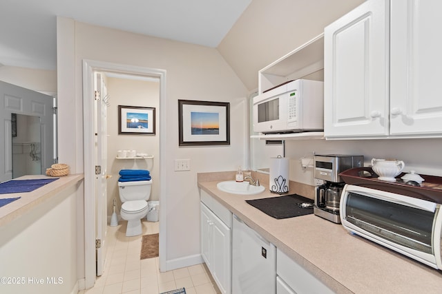 interior space featuring toilet, vanity, tile patterned floors, and lofted ceiling