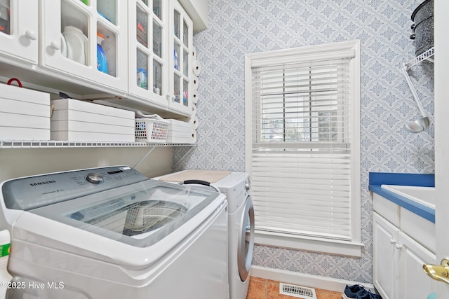 clothes washing area featuring cabinets, sink, washing machine and dryer, and tile patterned floors