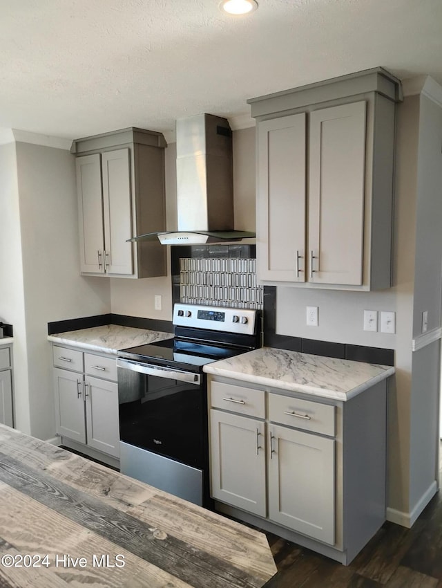 kitchen with stainless steel electric stove, dark hardwood / wood-style flooring, gray cabinetry, and wall chimney range hood