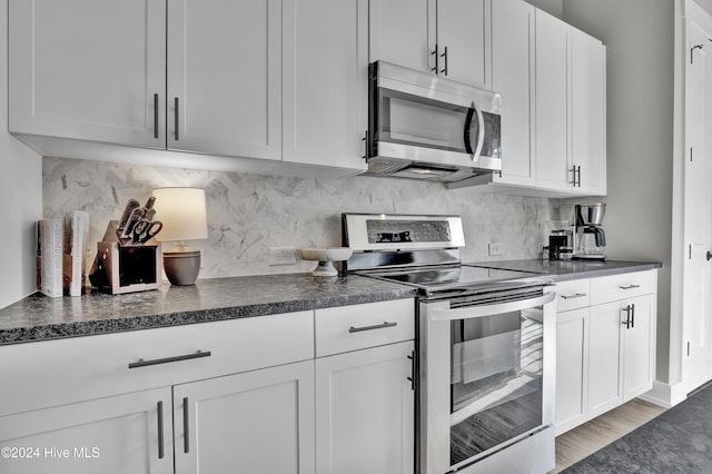 kitchen featuring white cabinets, light wood-type flooring, backsplash, and appliances with stainless steel finishes