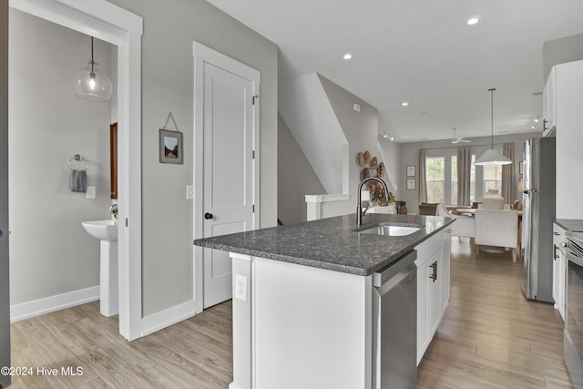 kitchen with appliances with stainless steel finishes, a kitchen island with sink, sink, pendant lighting, and white cabinets