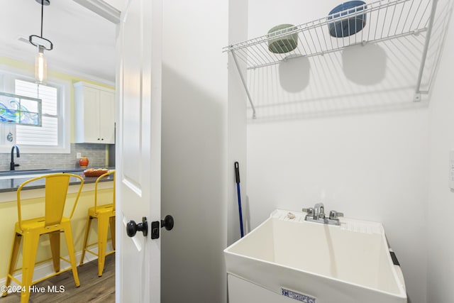 laundry room with hardwood / wood-style flooring, crown molding, and sink