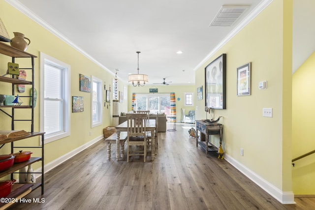 dining space featuring ceiling fan with notable chandelier, dark hardwood / wood-style flooring, and crown molding