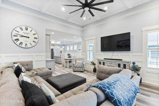 living room with beamed ceiling, light wood-type flooring, ceiling fan, and ornamental molding