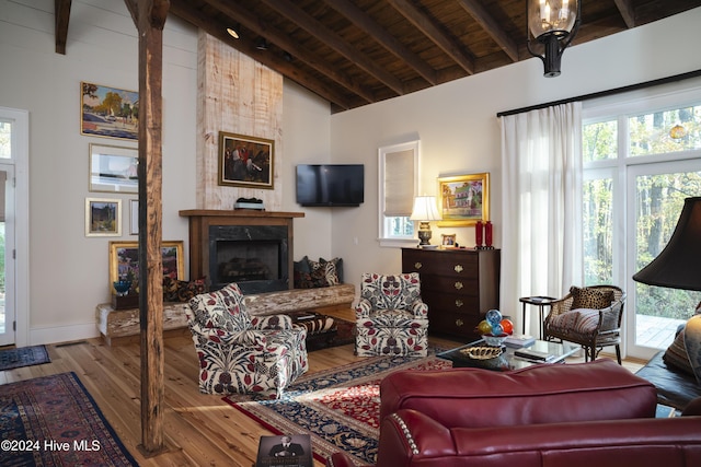 living room with hardwood / wood-style floors, vaulted ceiling with beams, a premium fireplace, and wooden ceiling