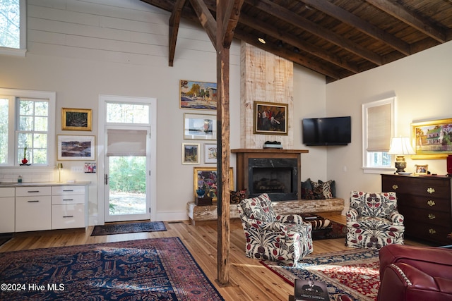 living room featuring beamed ceiling, plenty of natural light, light hardwood / wood-style floors, and high vaulted ceiling