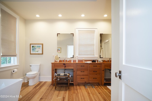 bathroom featuring hardwood / wood-style flooring, vanity, toilet, and a washtub