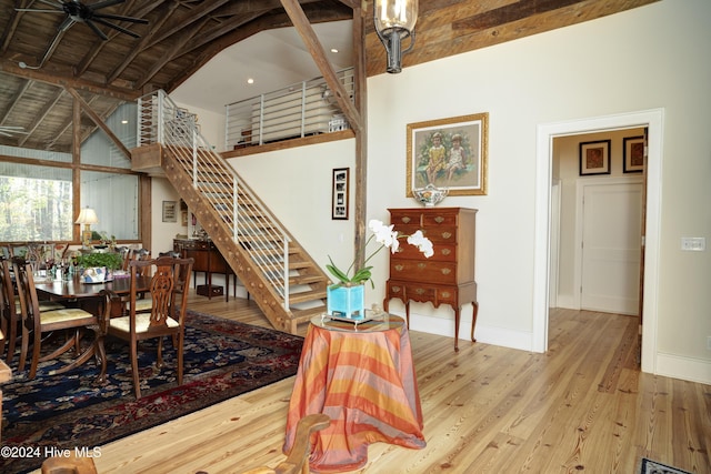 dining area featuring hardwood / wood-style flooring, ceiling fan, beam ceiling, and high vaulted ceiling