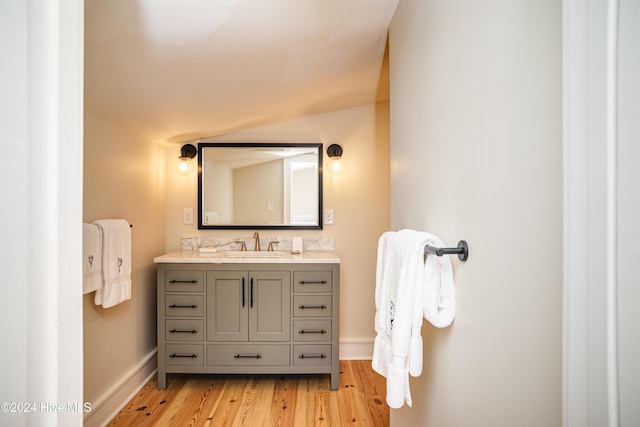 bathroom with vanity, hardwood / wood-style flooring, and vaulted ceiling