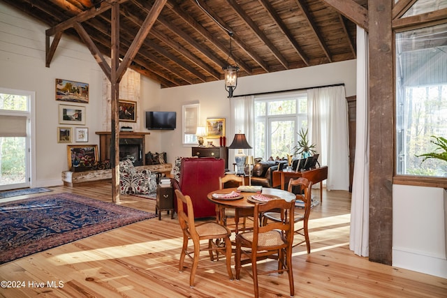 dining area featuring plenty of natural light, beamed ceiling, high vaulted ceiling, and light wood-type flooring