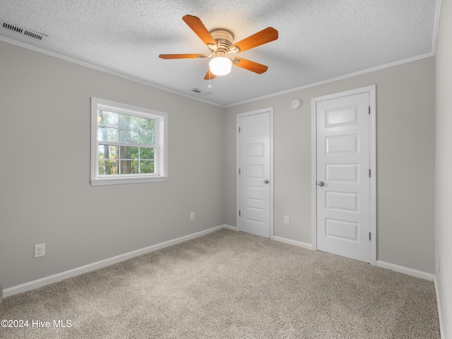 unfurnished bedroom with a textured ceiling, carpet floors, ceiling fan, and crown molding