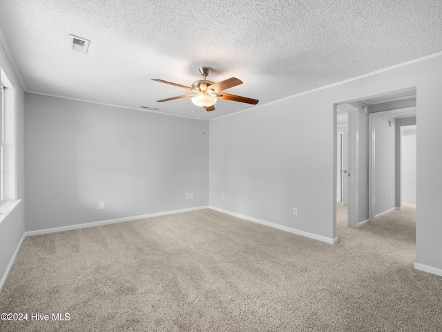 empty room featuring a textured ceiling, light colored carpet, and ceiling fan