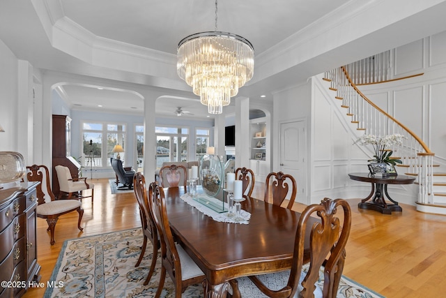 dining area featuring ceiling fan with notable chandelier, crown molding, and light wood-type flooring