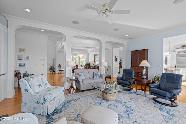 living room featuring ceiling fan, ornamental molding, and light hardwood / wood-style floors