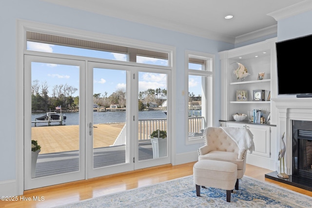 doorway to outside with a wealth of natural light, light hardwood / wood-style flooring, and crown molding