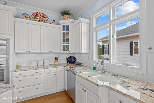 kitchen featuring sink, white cabinetry, stainless steel dishwasher, and crown molding