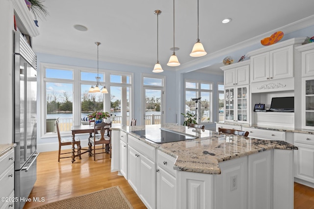 kitchen with white cabinets, a center island, stainless steel built in fridge, hanging light fixtures, and black electric cooktop