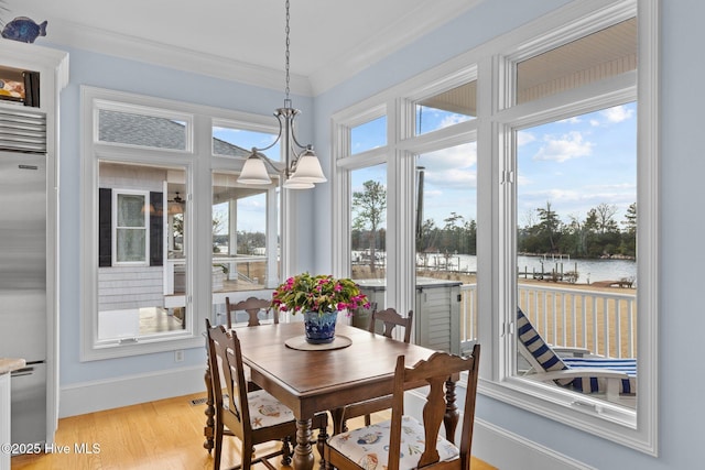 sunroom / solarium featuring an inviting chandelier and a water view