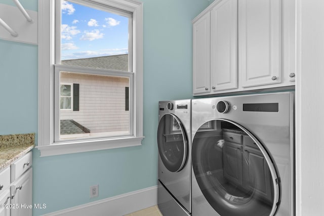 washroom featuring light tile patterned floors, cabinets, washing machine and clothes dryer, and a healthy amount of sunlight