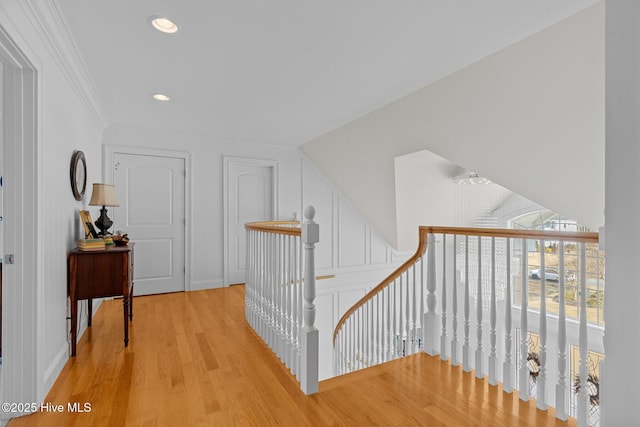 hallway with ornamental molding and light hardwood / wood-style floors