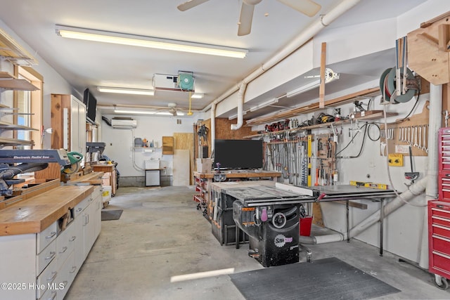 garage featuring ceiling fan, an AC wall unit, and a workshop area