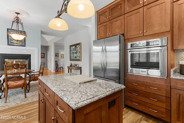 kitchen featuring light hardwood / wood-style flooring, a kitchen island, stainless steel appliances, and decorative light fixtures