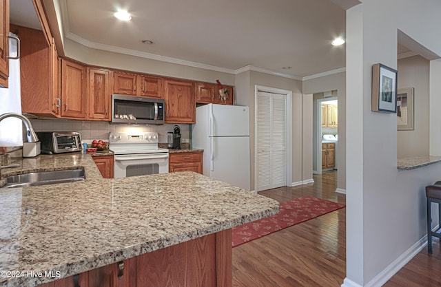 kitchen with dark hardwood / wood-style floors, sink, white appliances, and kitchen peninsula