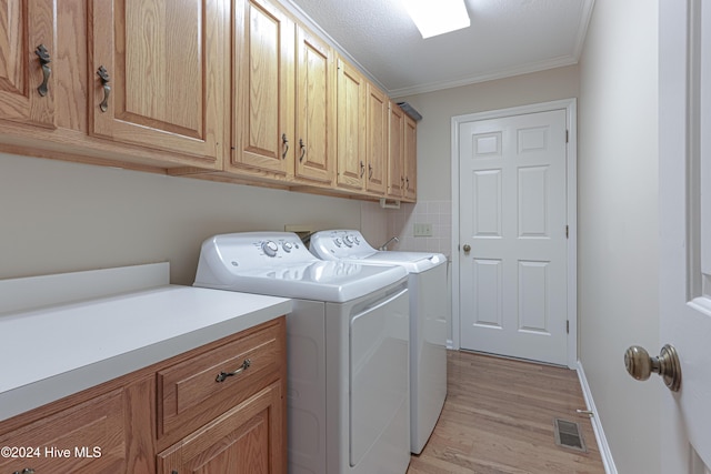 washroom with washer and clothes dryer, cabinets, crown molding, light hardwood / wood-style flooring, and a textured ceiling