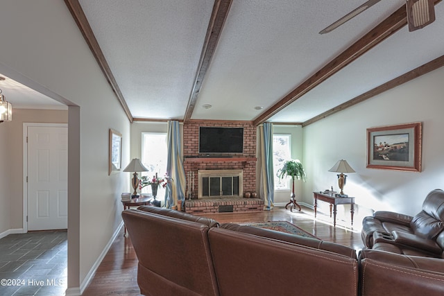 living room featuring a fireplace, a textured ceiling, lofted ceiling with beams, and crown molding