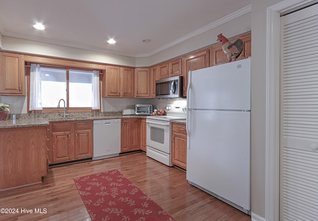 kitchen with white appliances, sink, crown molding, light hardwood / wood-style flooring, and light stone counters