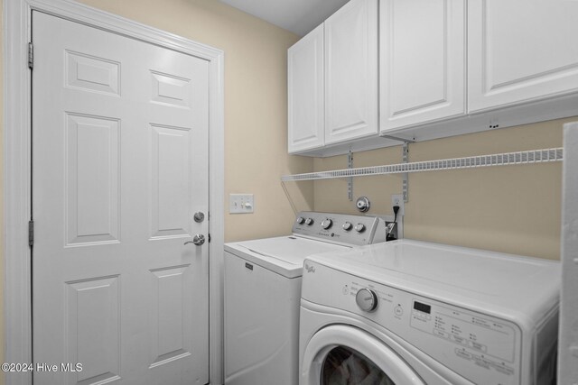 clothes washing area with washing machine and clothes dryer and cabinets