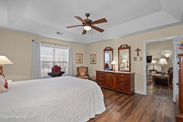 bedroom featuring dark hardwood / wood-style floors, a raised ceiling, and ceiling fan