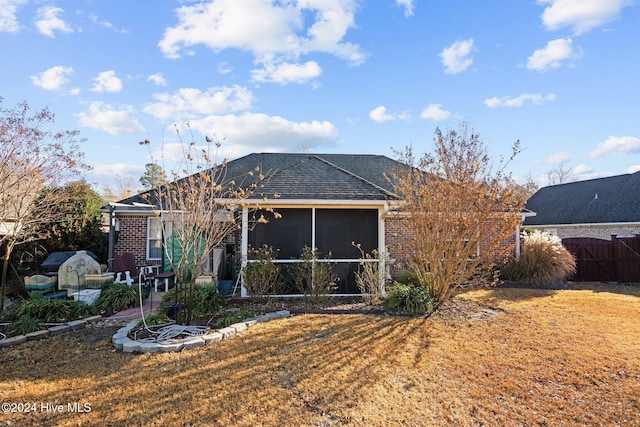 rear view of house featuring a lawn and a sunroom