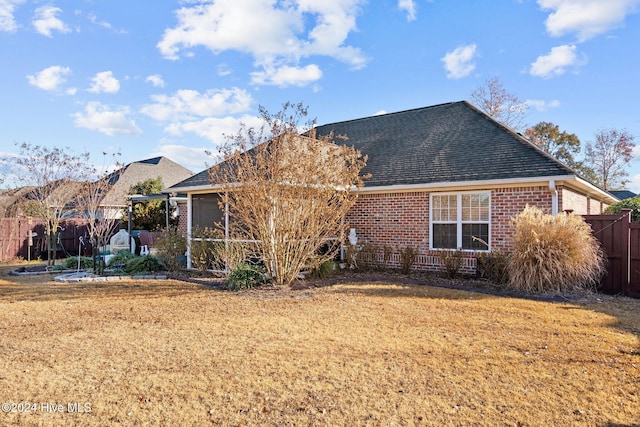 rear view of property featuring a sunroom and a yard