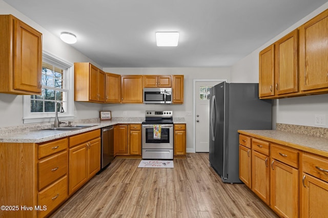 kitchen with stainless steel appliances, light hardwood / wood-style floors, and sink