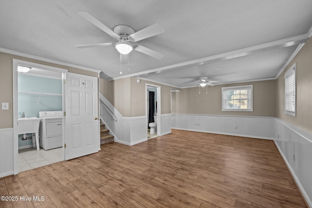 empty room featuring ceiling fan, washer / dryer, ornamental molding, and light wood-type flooring