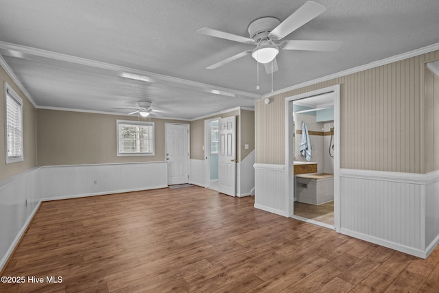 empty room with ceiling fan, a wealth of natural light, crown molding, and hardwood / wood-style floors