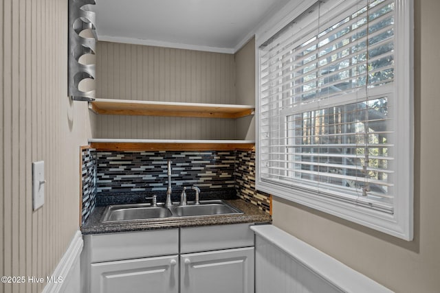 kitchen with sink, backsplash, white cabinets, and ornamental molding