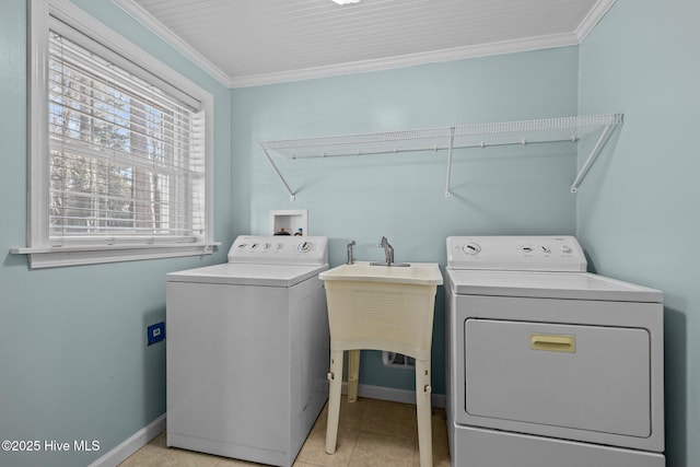 washroom with light tile patterned floors, washer and dryer, crown molding, and sink