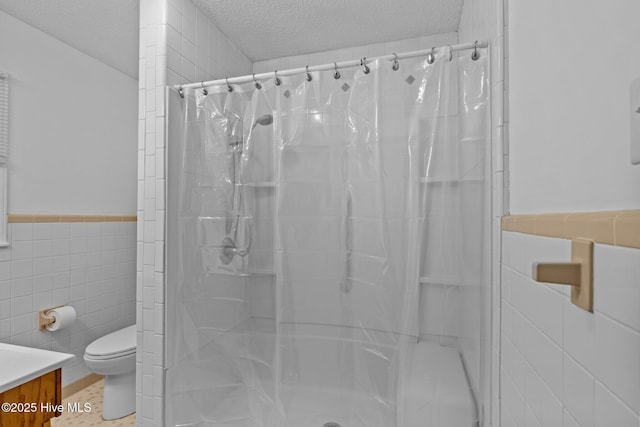 bathroom featuring a textured ceiling, vanity, tile walls, toilet, and a shower with shower curtain