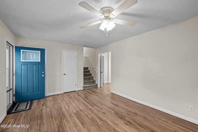 foyer entrance featuring ceiling fan, a textured ceiling, and light hardwood / wood-style flooring