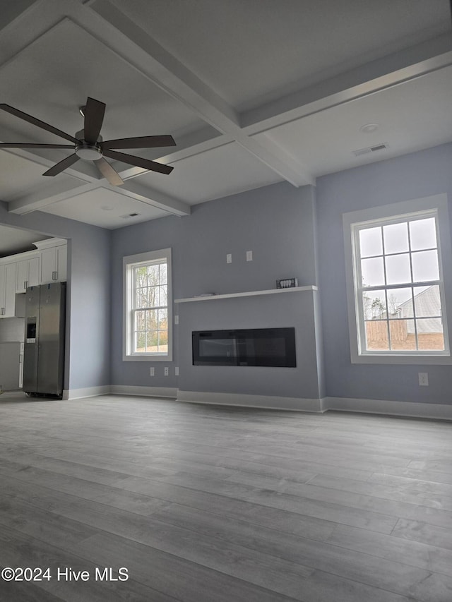 unfurnished living room with beamed ceiling, ceiling fan, and light hardwood / wood-style flooring