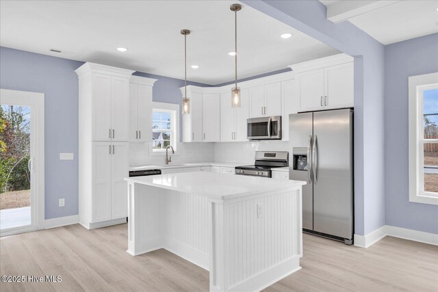 kitchen with white cabinets, stainless steel refrigerator with ice dispenser, hanging light fixtures, light hardwood / wood-style floors, and a kitchen island