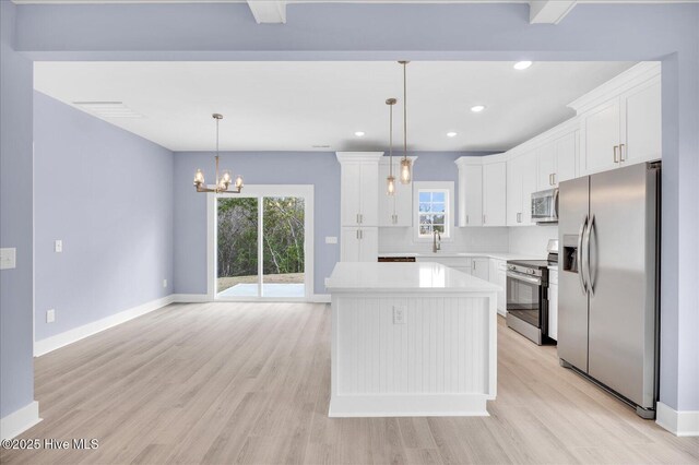 kitchen featuring stainless steel appliances, white cabinetry, a kitchen island, and hanging light fixtures