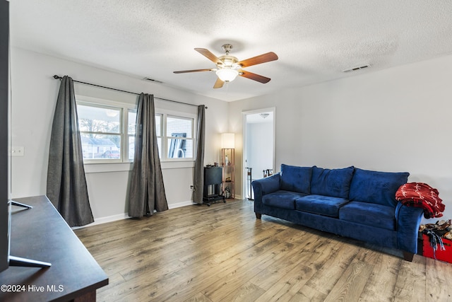 living room featuring wood-type flooring, a textured ceiling, and ceiling fan