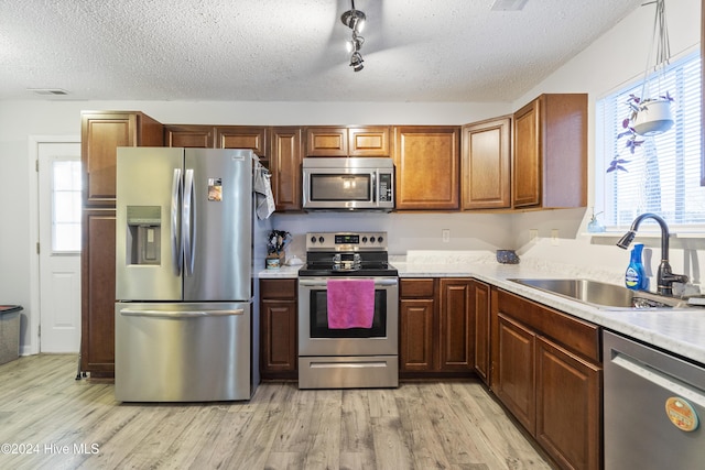 kitchen with plenty of natural light, sink, stainless steel appliances, and light hardwood / wood-style flooring