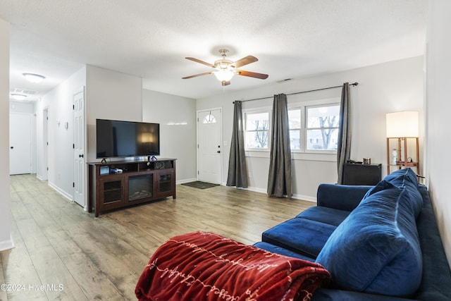 living room with hardwood / wood-style flooring, ceiling fan, and a textured ceiling